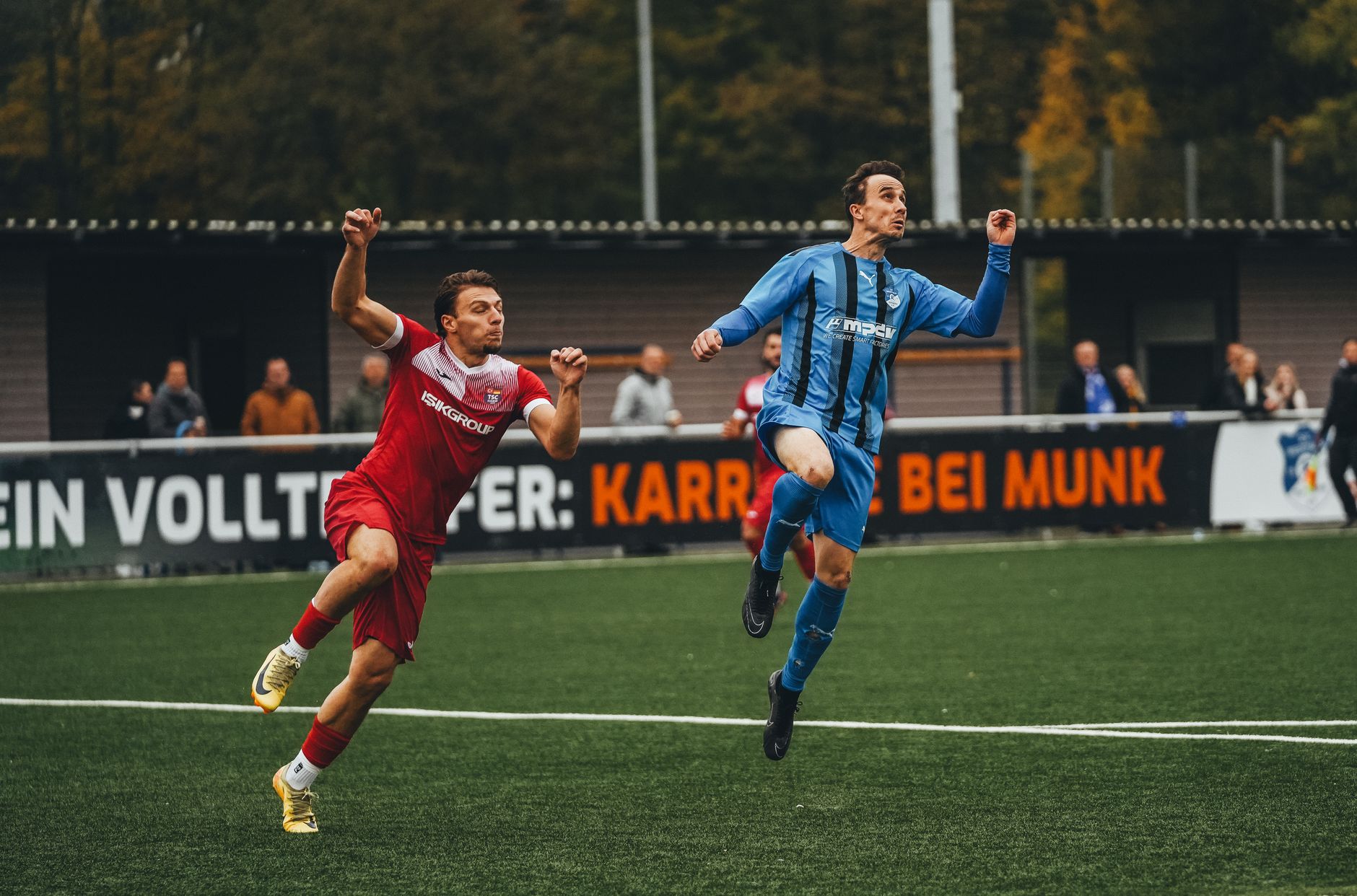Dua pemain sepak bola beraksi selama pertandingan kompetitif di lapangan hijau.