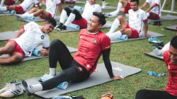 Pemain sepak bola yang melakukan latihan peregangan di lapangan berumput, Jakarta.