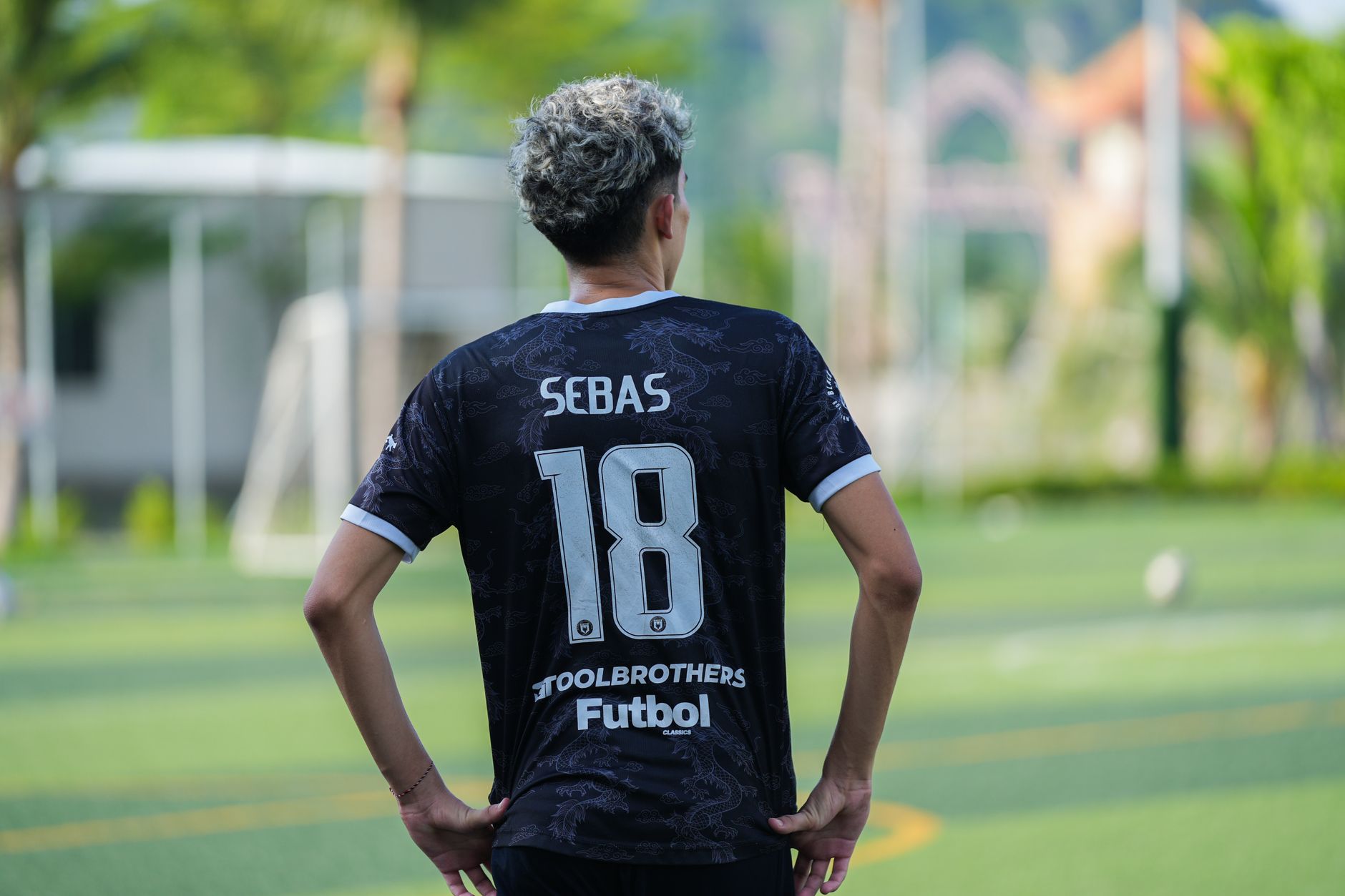 Tampilan belakang pemain sepak bola yang mengenakan jersey nomor 18 di hari yang cerah di luar ruangan.