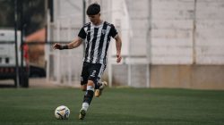 Seorang pemain sepak bola muda sedang beraksi, menggiring bola selama pertandingan di lapangan.