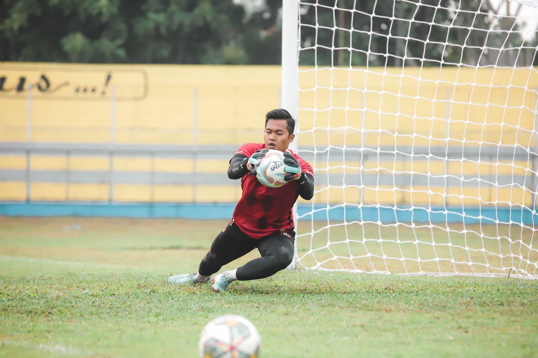 Seorang kiper sepak bola melakukan penyelamatan dinamis selama pertandingan di luar ruangan di Jakarta, Indonesia.