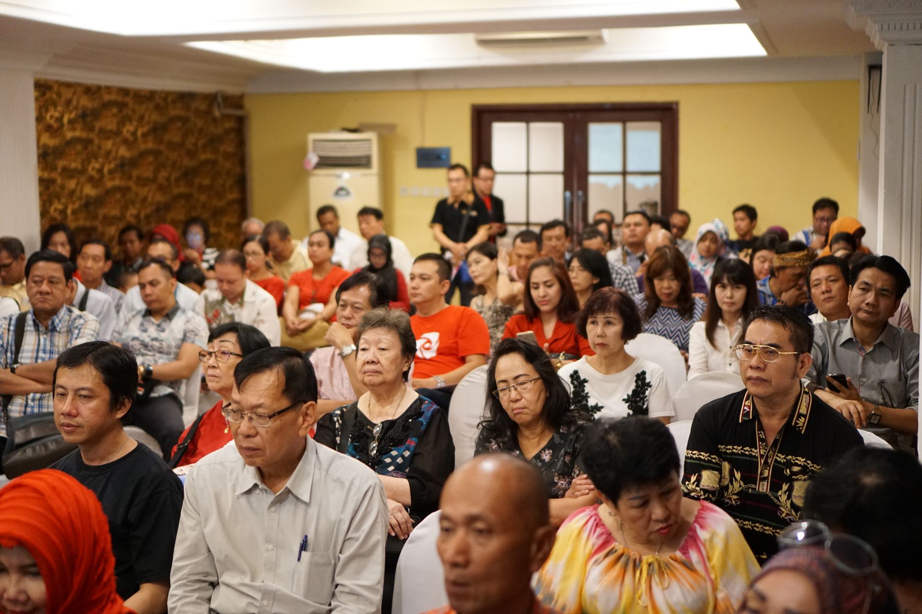 Sekelompok orang dewasa yang beragam menghadiri konferensi di sebuah pengaturan dalam ruangan di Indonesia.