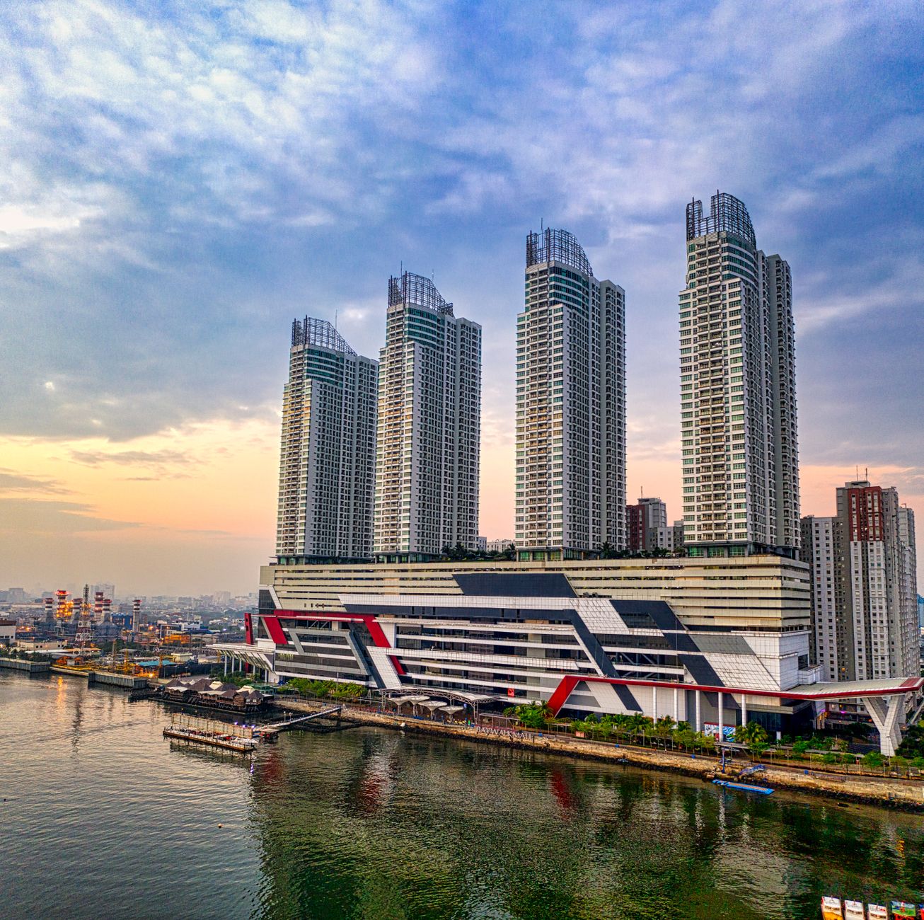 Pemandangan udara gedung pencakar langit modern di Jakarta, Indonesia, saat matahari terbit yang tercermin di air.