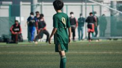 Pemain sepak bola muda dengan jersey hijau di lapangan sepak bola saat pertandingan.