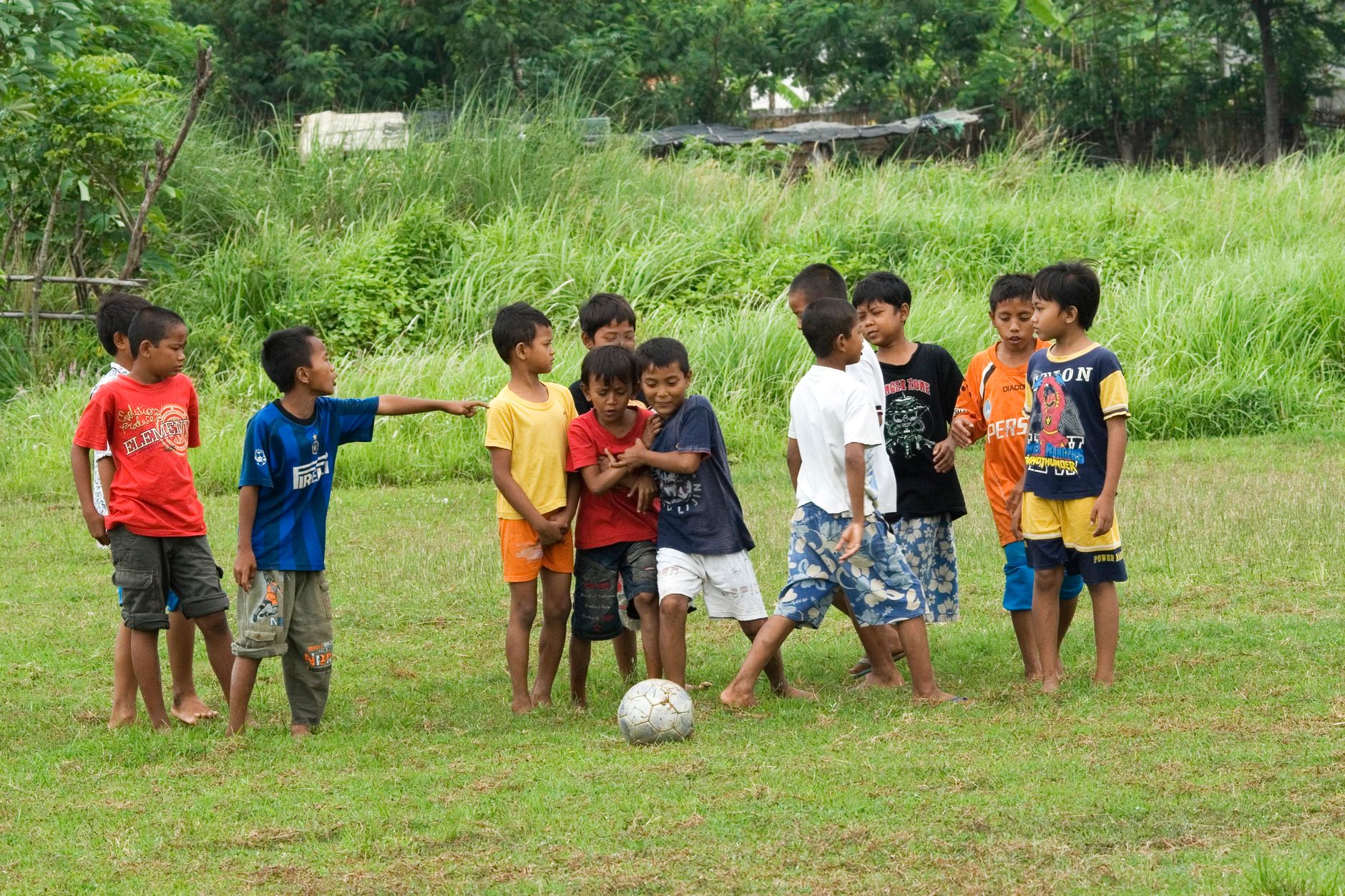 Sekelompok anak laki-laki bermain sepak bola di lapangan rumput, menunjukkan kerja sama tim dan kesenangan.