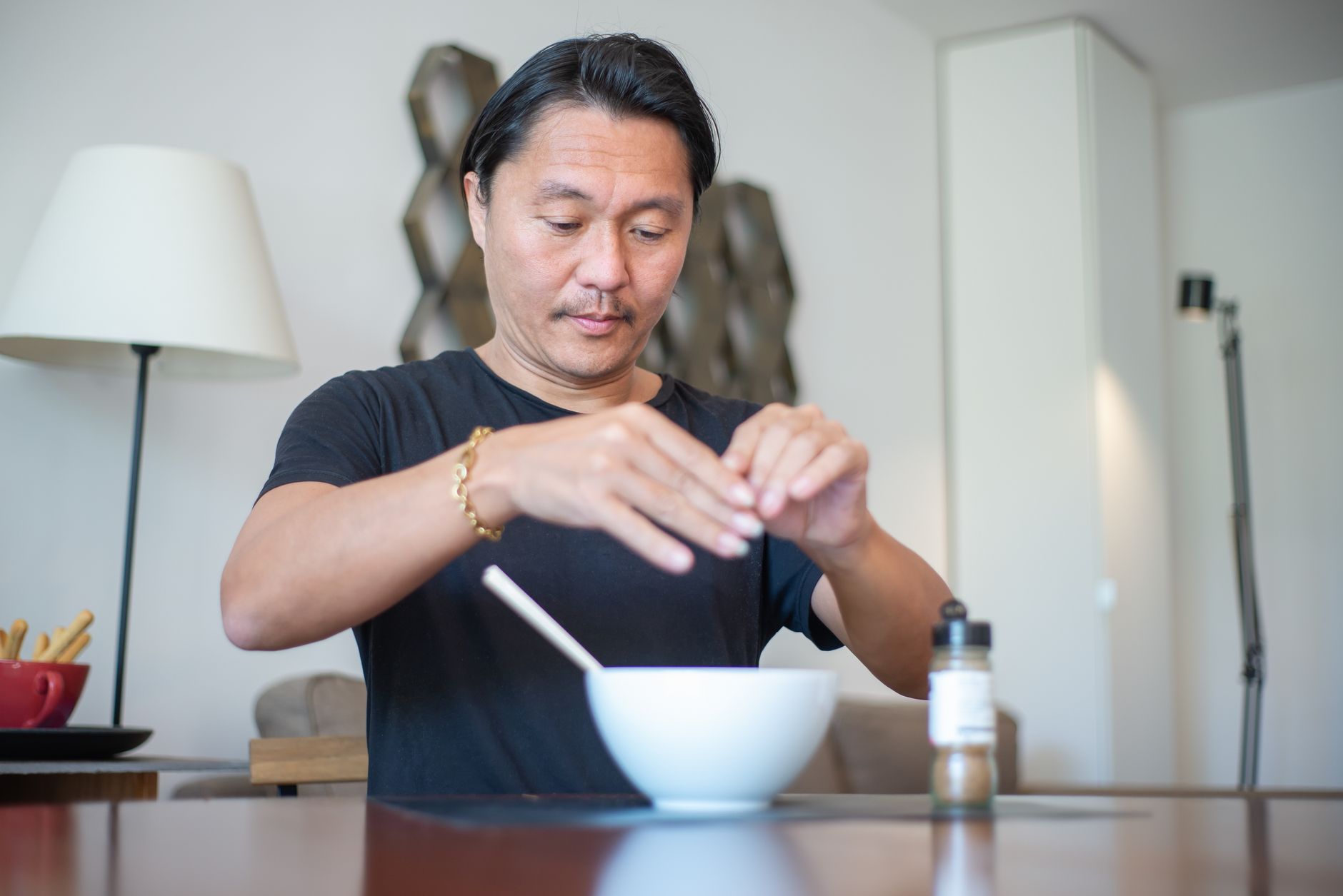 Pria Asia yang menyiapkan makanan di dalam ruangan di dapur kontemporer dengan fokus pada tangan.