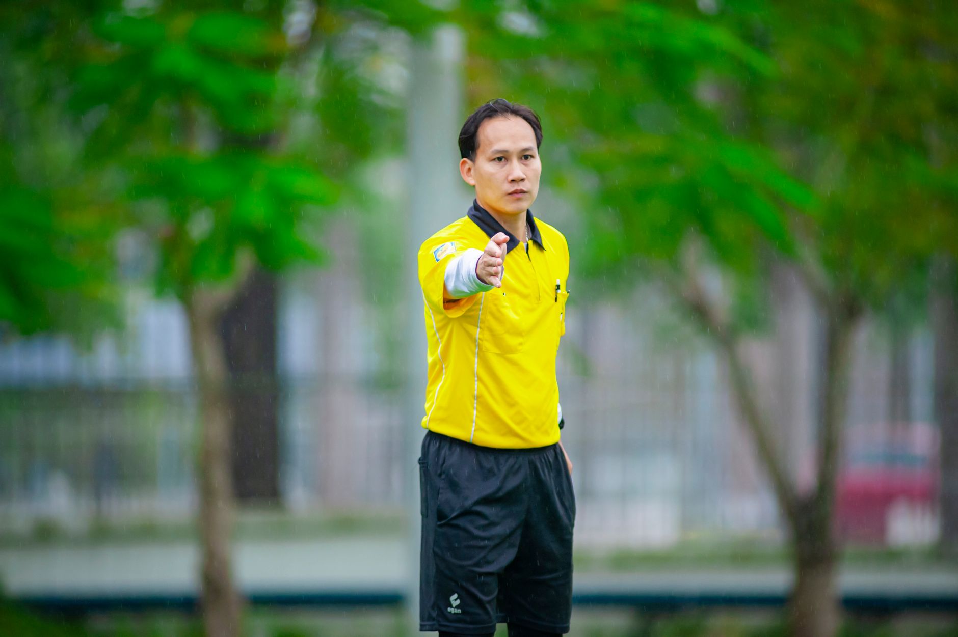 Wasit memberi isyarat selama pertandingan sepak bola di Hanoi, Vietnam, di lapangan hijau.